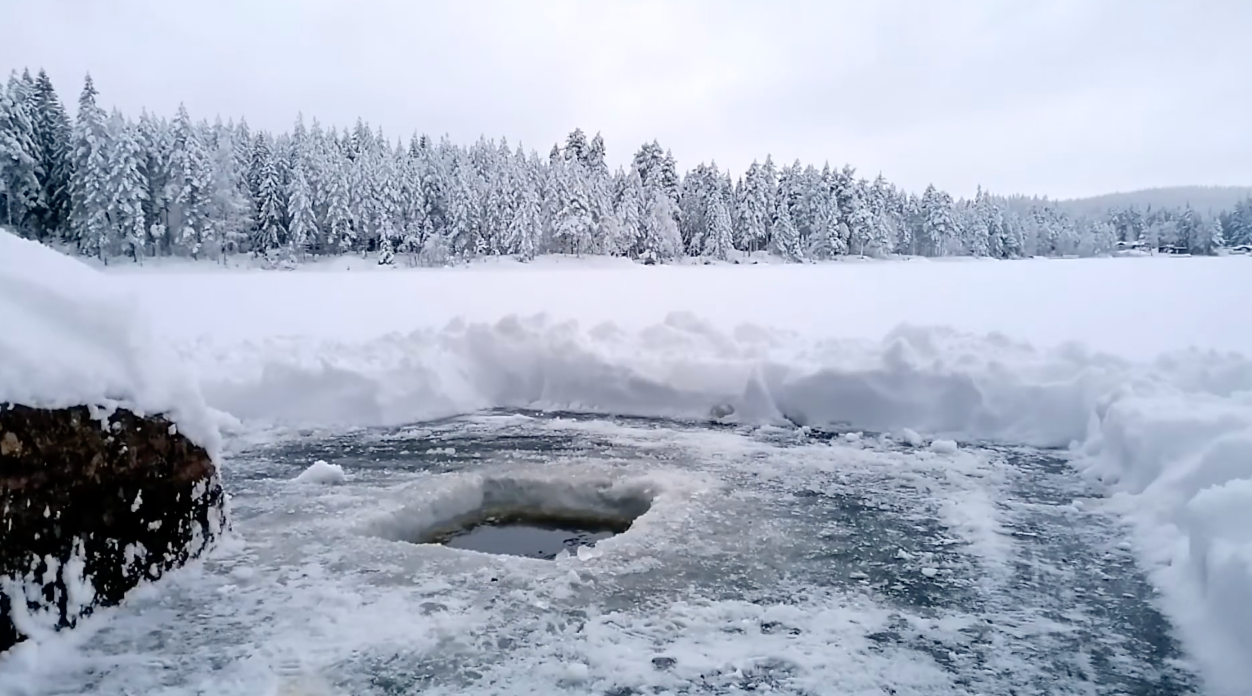 Ein geöffnetes Eisloch in einer tief verschneiten Winterlandschaft