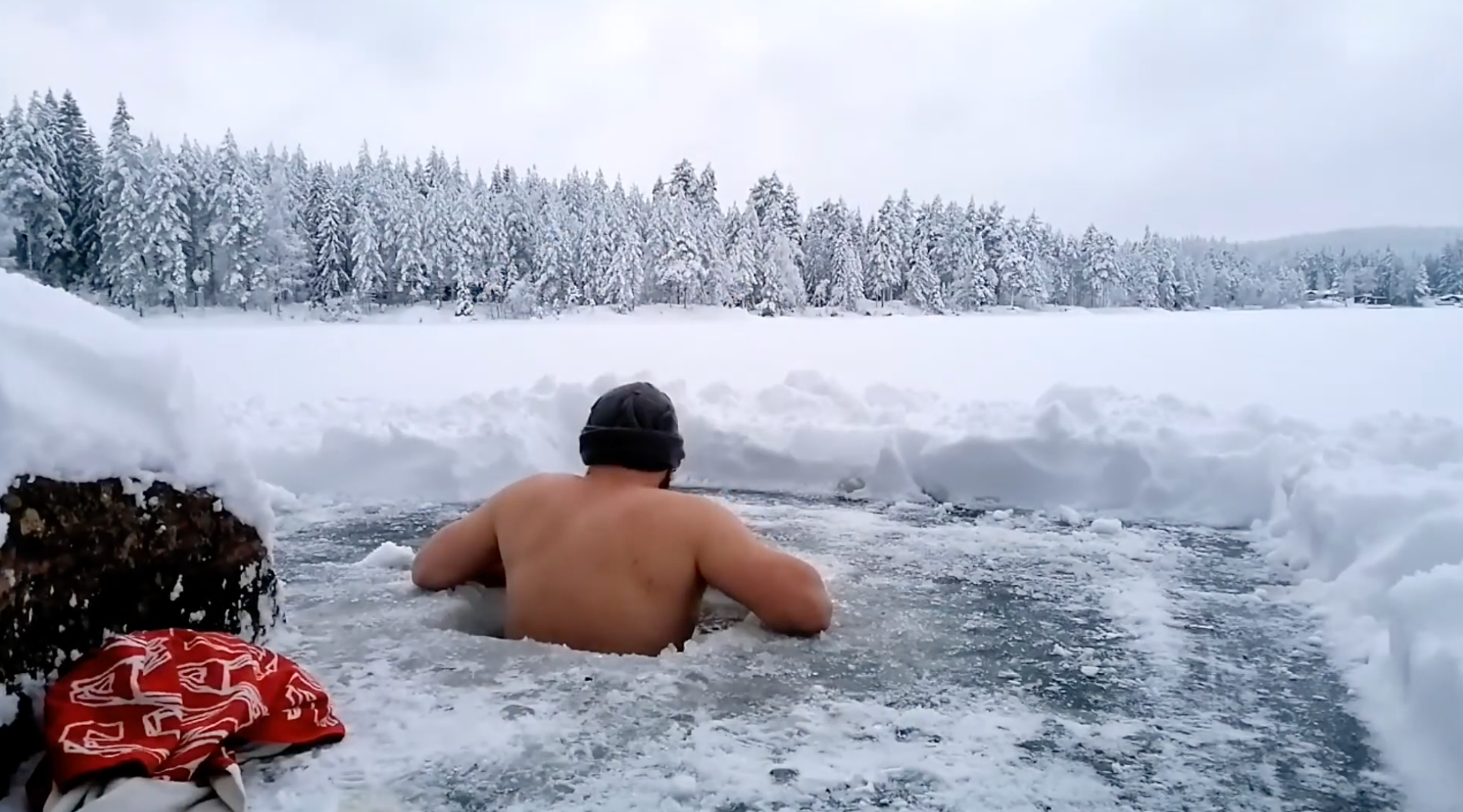 Ein Mann sitzt in einem Eisloch in einem verschneiten See